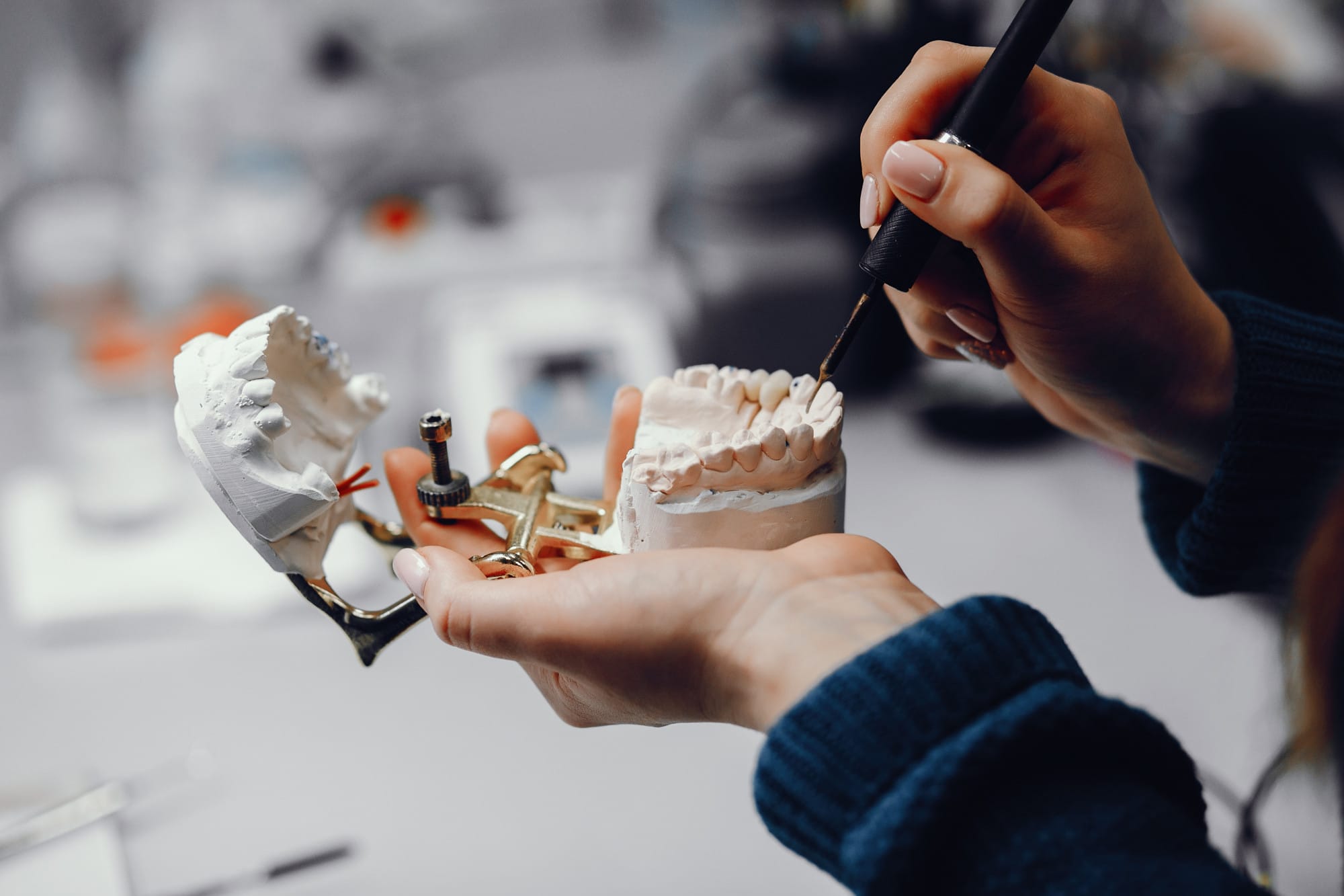 Diş teknisyeni protez ve implant için diş kalıbı üzerinde detaylı çalışma yapıyor