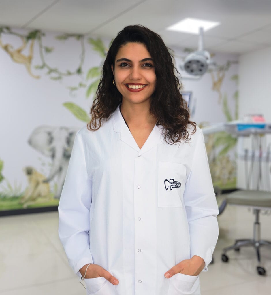 Dt. Nilay Gül Budak, Antalya MRV Dental kliniğinde beyaz önlükle gülümseyen diş hekimi portresi