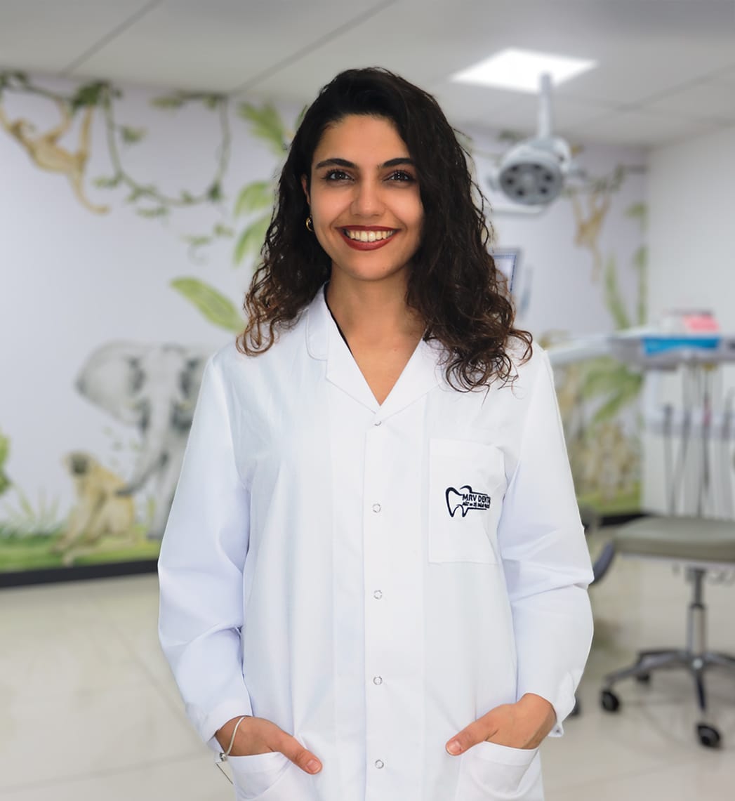 Dt. Nilay Gül Budak, Antalya MRV Dental kliniğinde beyaz önlükle gülümseyen diş hekimi portresi