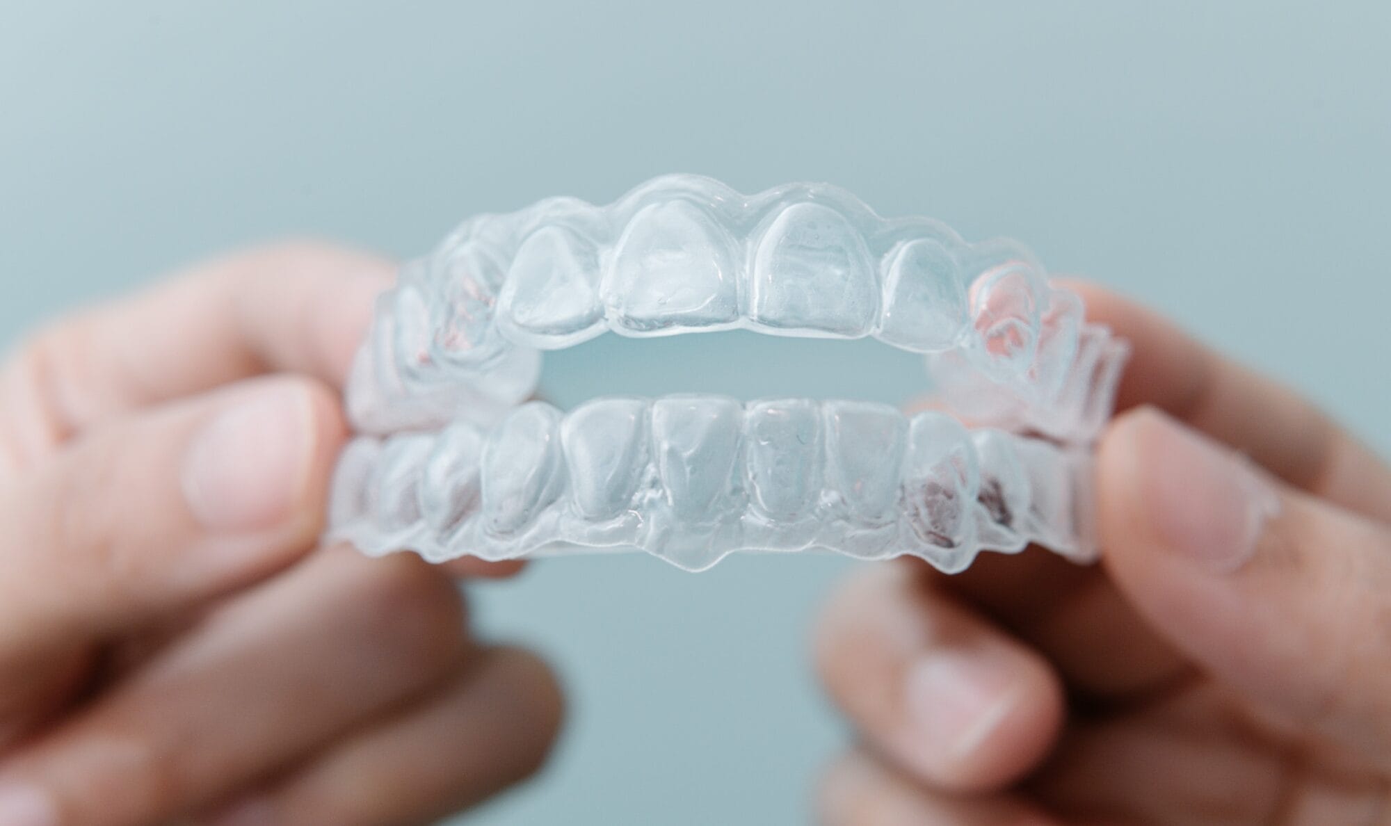 Invisalign tedavisinde kullanılan iki adet şeffaf plak, ellerde tutulurken yakın çekim